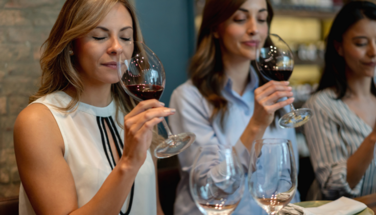 3 femmes qui sentent du vin rouge au verre