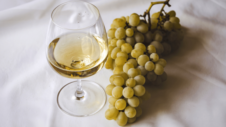 Verre de vin blanc Gros Manseng à côté d'une grappe de raison